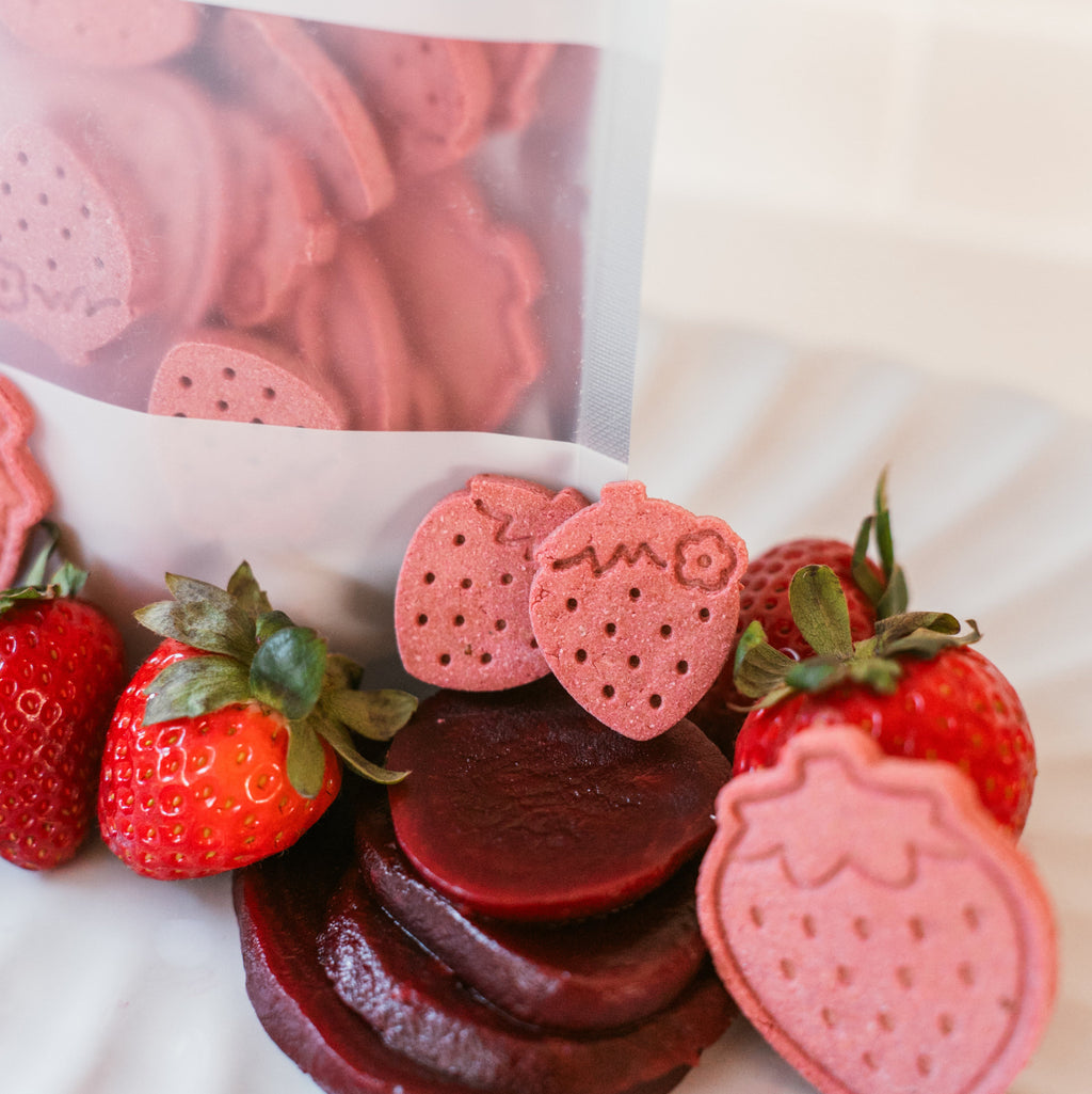 Close-up of Berry Beet Bites biscuits with packaging and fresh strawberries