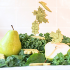 Leaf-shaped dog biscuits falling over fresh pear and greens