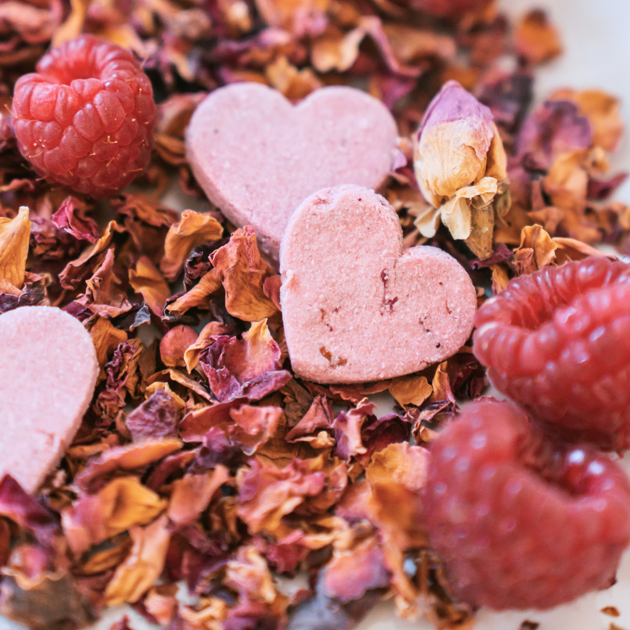 Close up of raspberry heart dog biscuits with rose petals, all natural handmade dog treats with floral ingredients